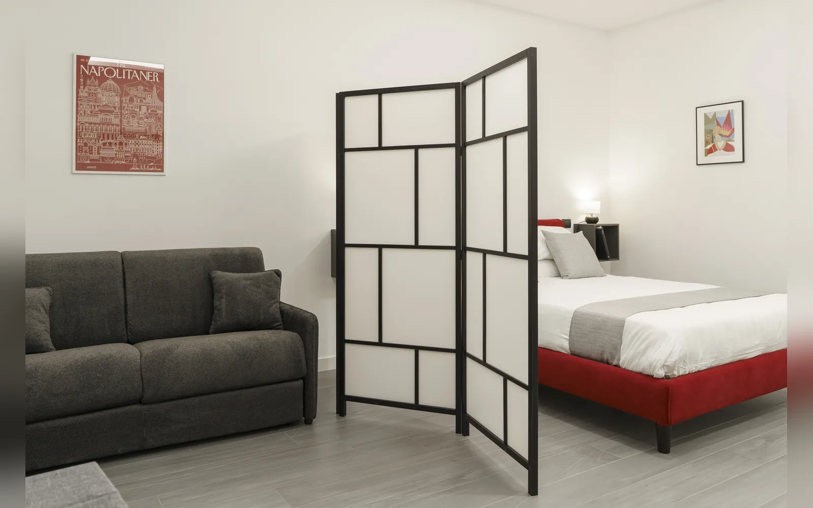 Il divano grigio, il paravento e il letto rosso